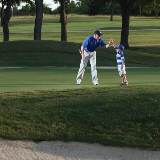 A man and a child on a golf course.