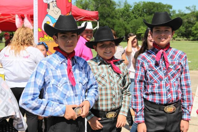 Three boys in cowboy hats standing next to each other.