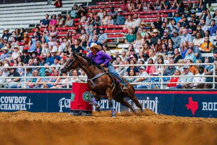 A woman riding a horse in a rodeo arena.