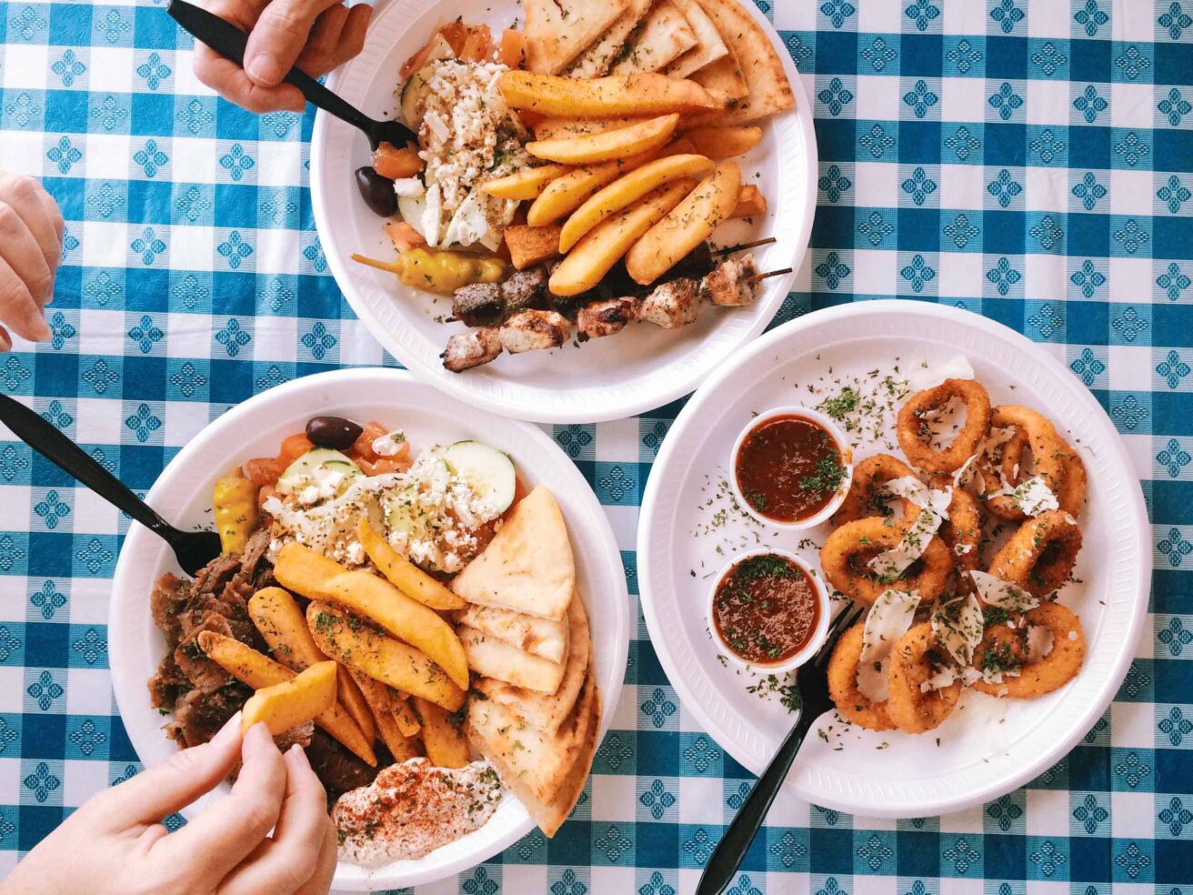 Three plates of food on a table with a checkered tablecloth.