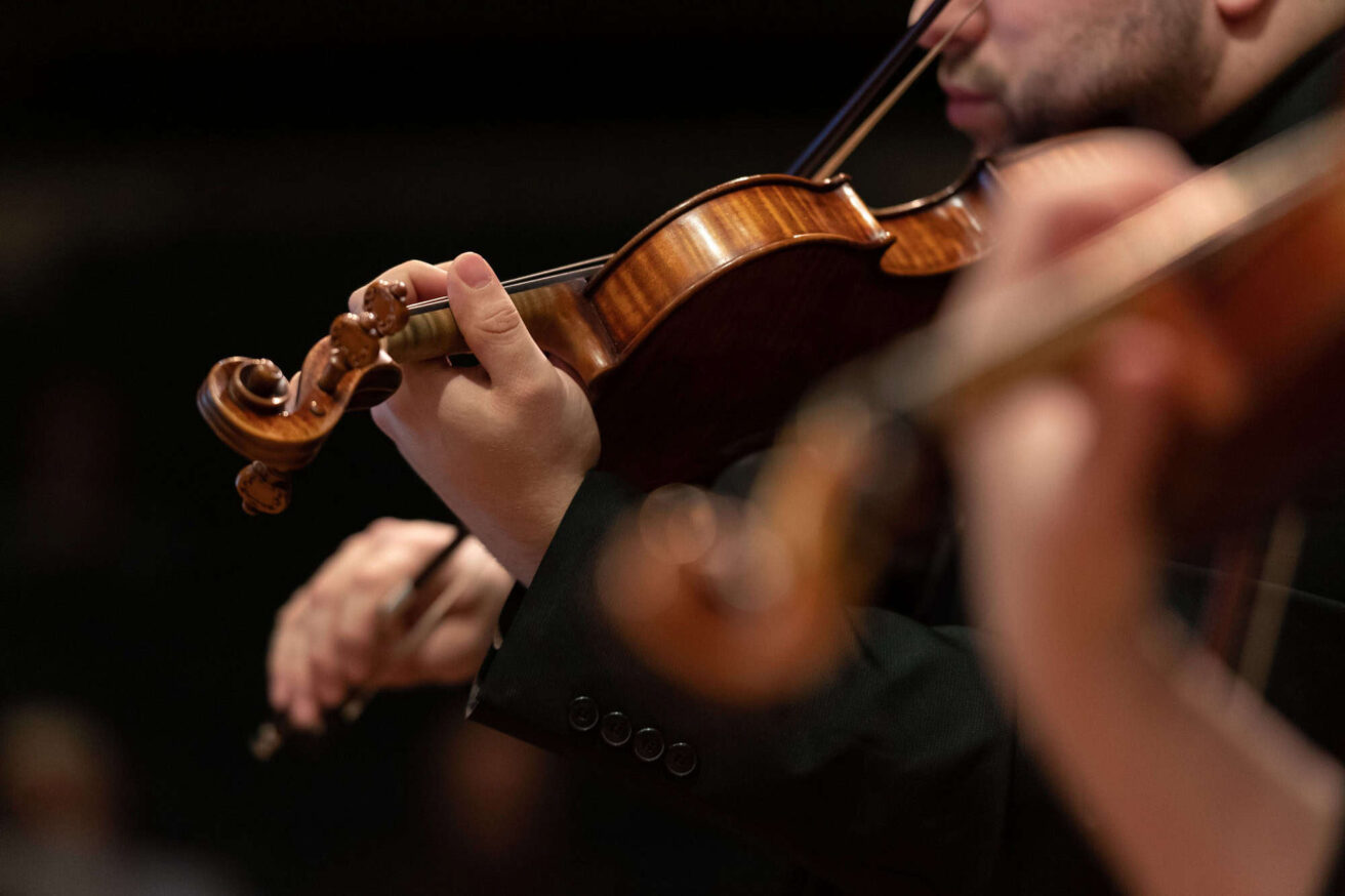 A close up of a person playing a violin.