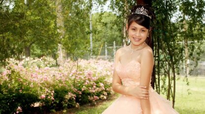 A young girl in a pink dress posing for a picture.