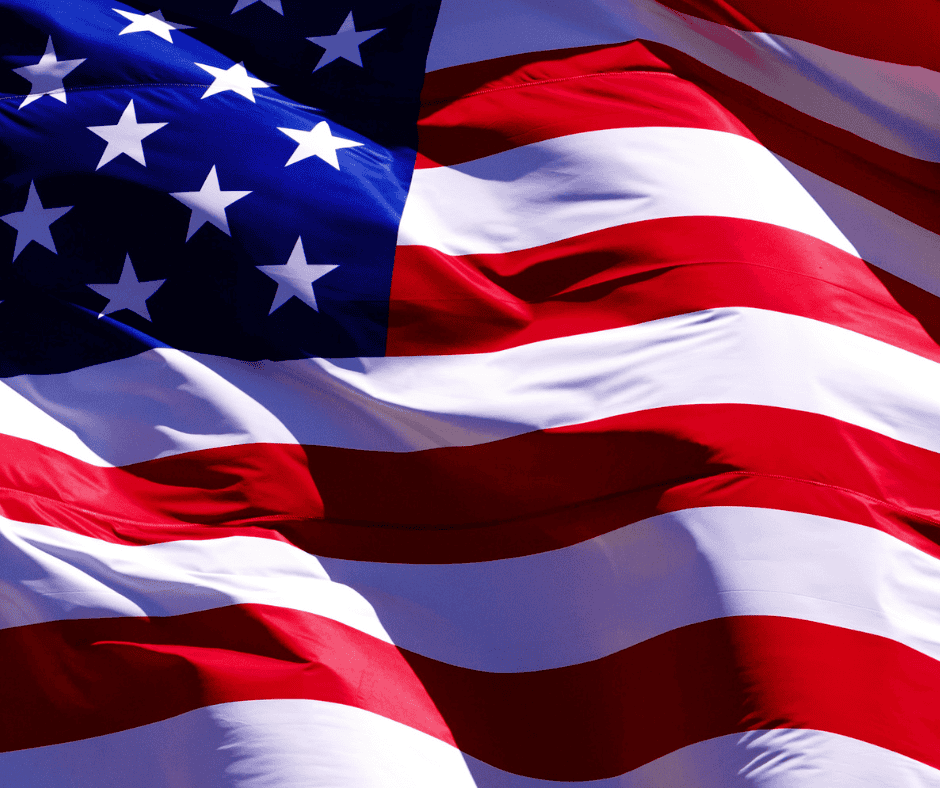 Close-up of the United States flag showing a section of blue with white stars and alternating red and white stripes waving gently.