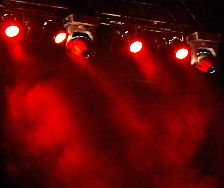 Red stage lights illuminate smoke against a dark background.