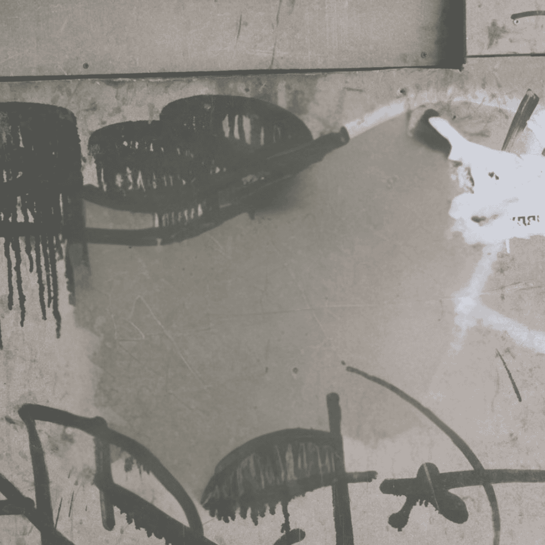 Graffiti on a concrete wall featuring abstract black and white shapes and lines, with some paint drips visible.